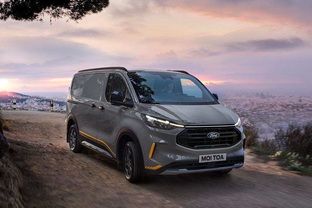 Szürke Ford Transit Custom Trail sárga dekorcsíkokkal.