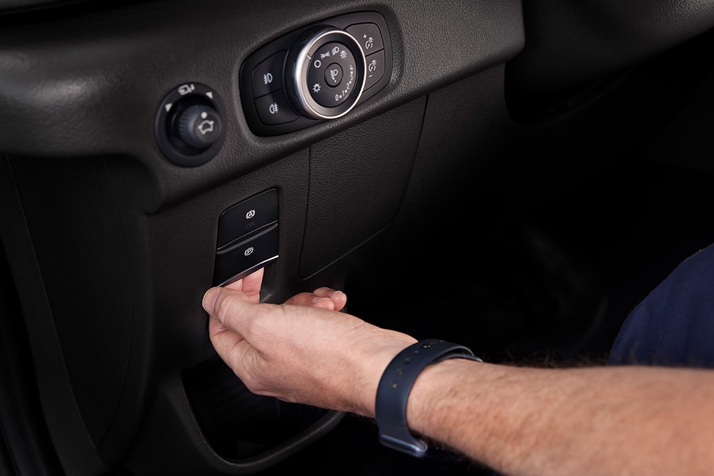 Közelkép egy kézről, amint megnyom egy gombot egy Ford E-Transit elektromos áruszállító műszerfalán.