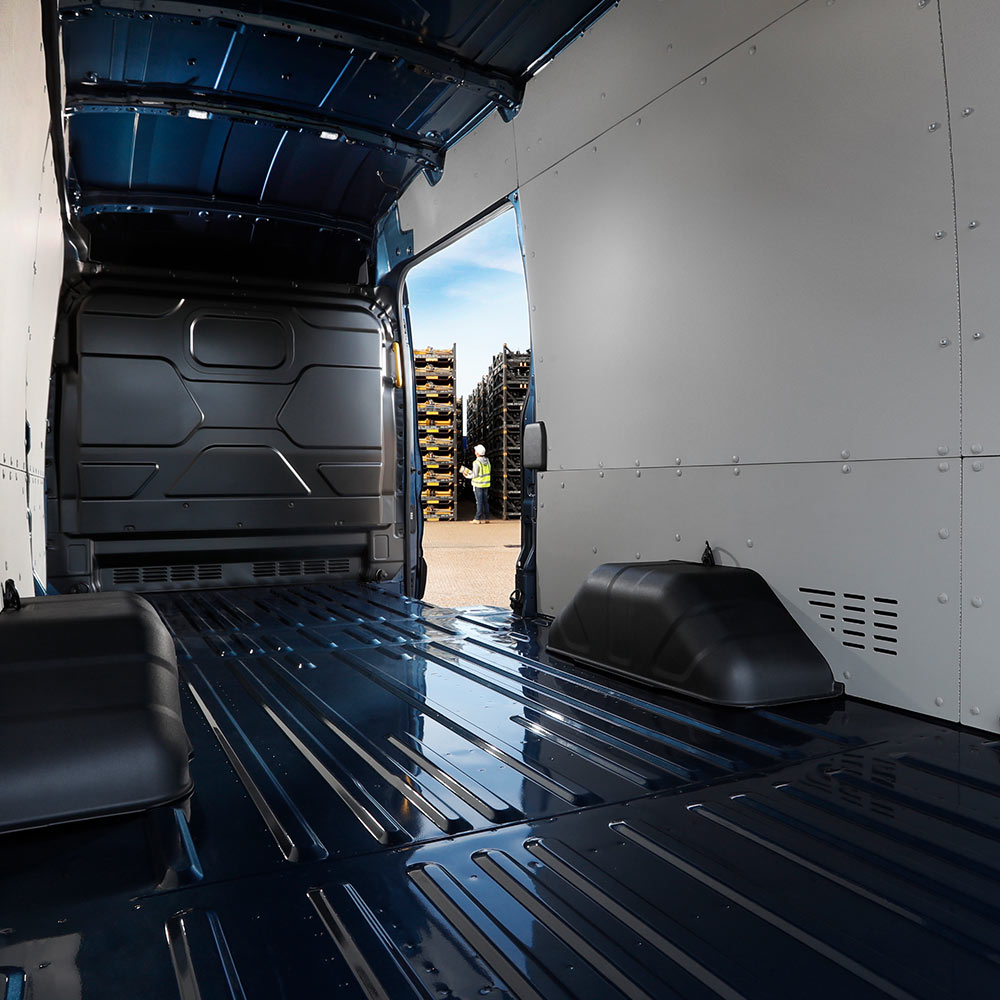 Egy Ford Transit áruszállító belső nézete, amelybe éppen rakományt pakolnak targoncával.