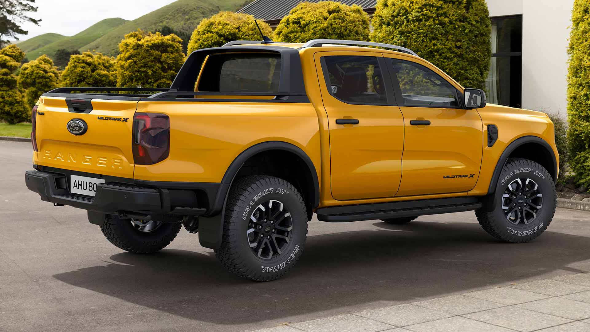 Egy duplakabinos, sárga Ford Ranger parkol egy aszfaltozott kocsifeljáró előtt.