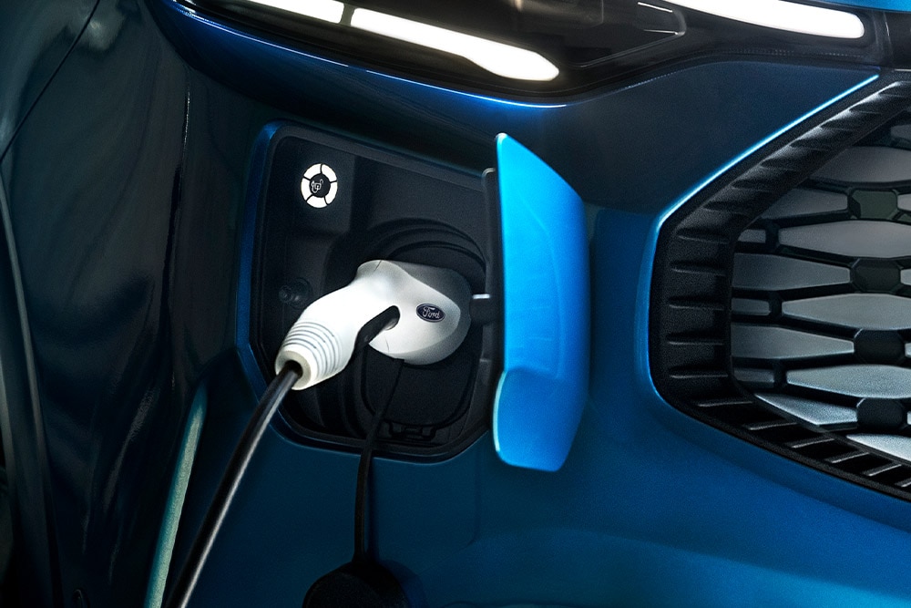 Kék Ford Transit plug-in hibrid töltés közben.