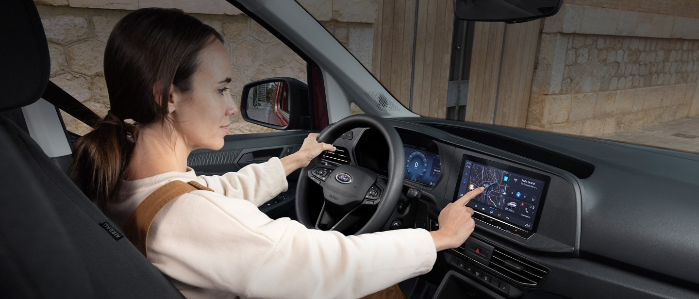 A vadonatúj Ford Transit Connect vezetőülésében ülő nő megérinti a 10"-os érintőképernyőt.