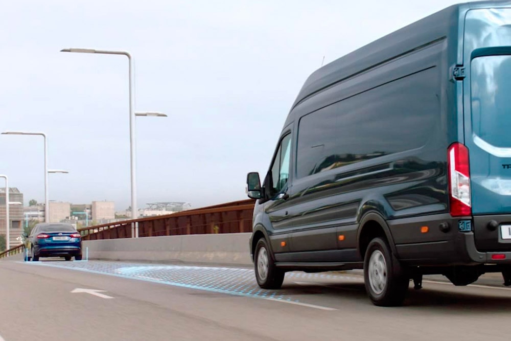 Egy kék Ford Transit Van, kék vonalakkal ábrázolva az úton a fejlett vezetéstámogató rendszerek működését.