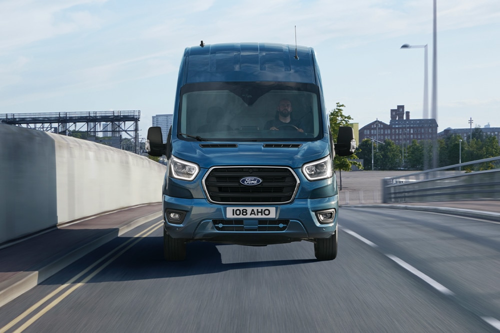 Egy kék Ford Transit Van elölnézete, amint egy úton halad.