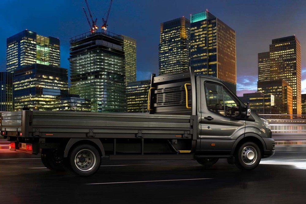 A Ford Transit fülkés alvázas áruszállító éjszaka egy városi úton.