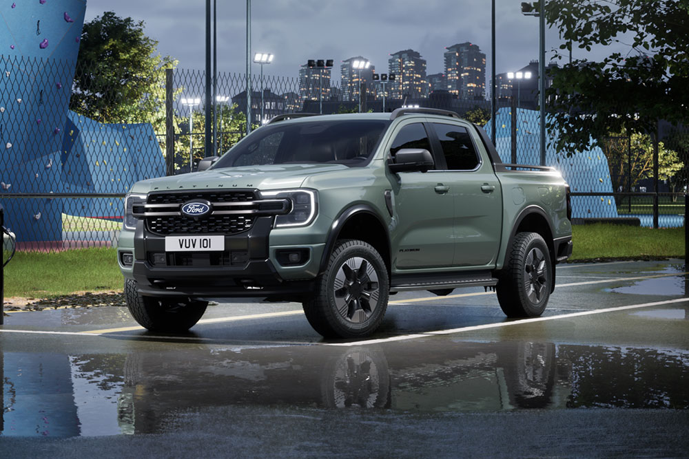 Szürke Ford Ranger PHEV parkol egy város látképe előtt alkonyatkor.