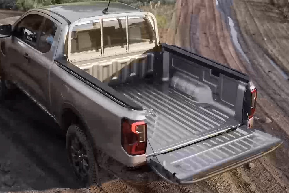 Ezüstszínű, nyújtottkabinos Ford Ranger XLT modellt látunk álló helyzetben sáros felületen, nyitott csomagtérajtóval, felülnézetből.