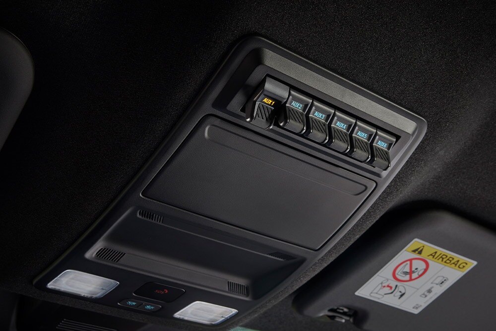 Közelkép a Ford Ranger platóján lévő elektromos aljzathoz kábelt csatlakoztató kézről.