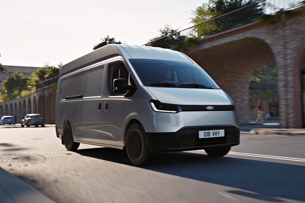 Fehér Ford Transit City® L2H2 áruszállító egy városban halad az úton.