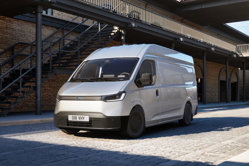 Fehér Ford Transit City® L2H2 áruszállító parkol egy téglaépület előtt.