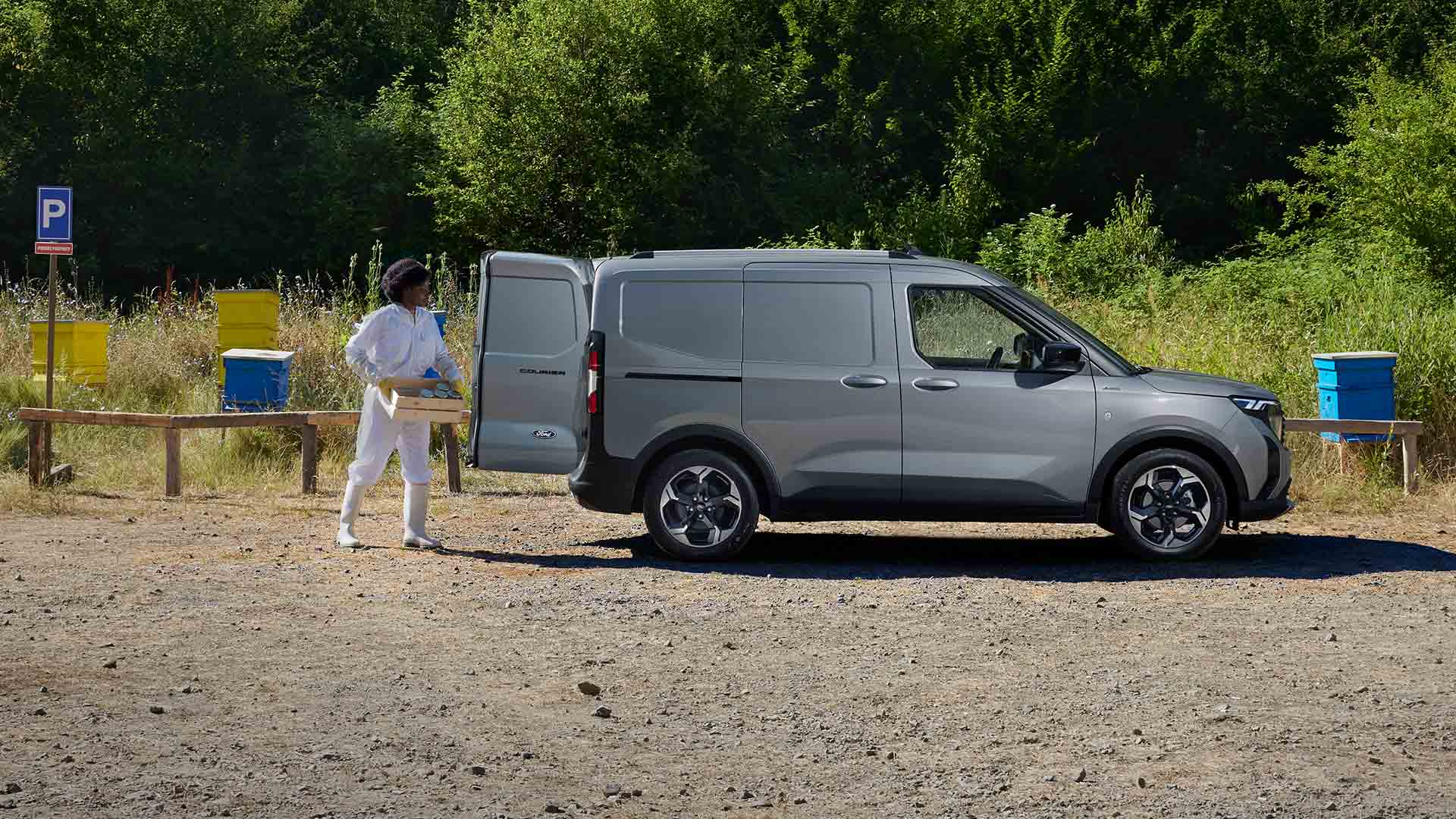 Méhész mézet pakol egy Ford Transit Courierba