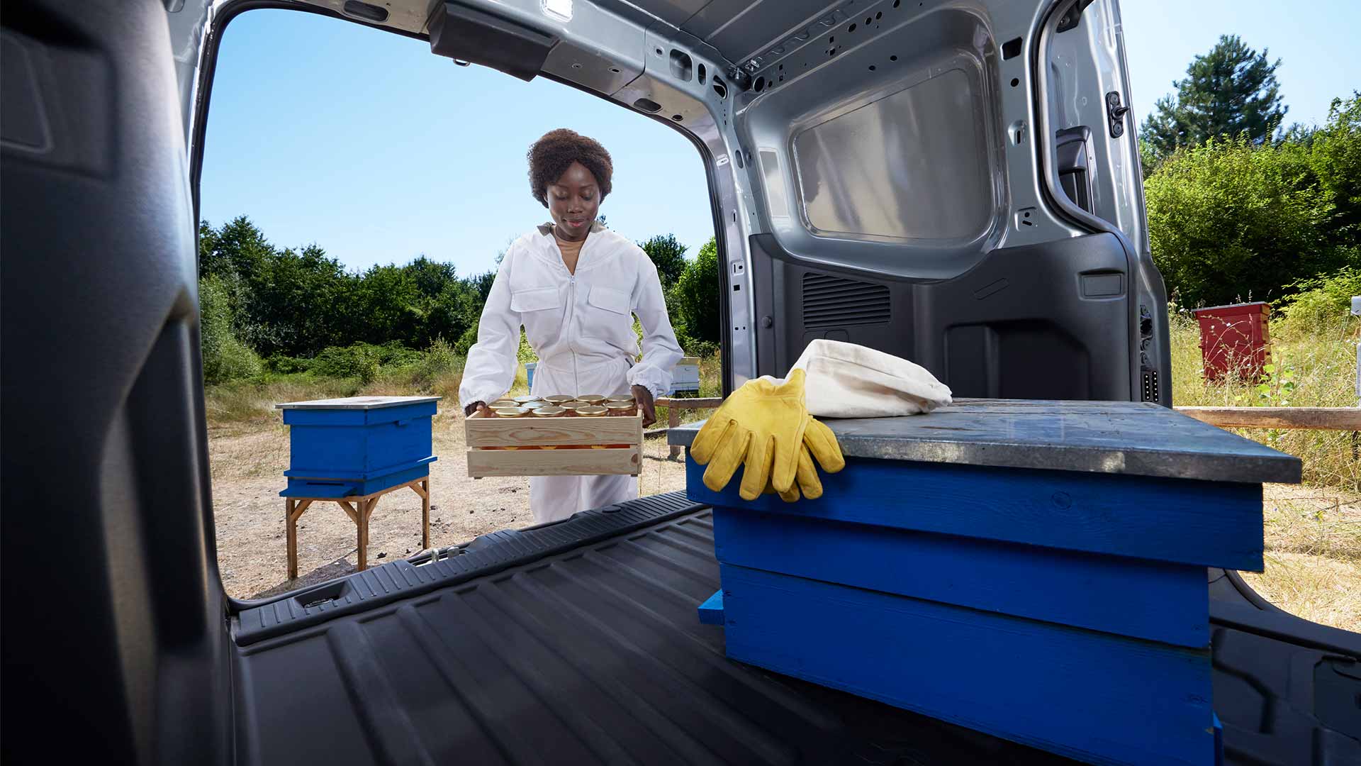 Méhész mézet pakol egy Ford Transit Courierba