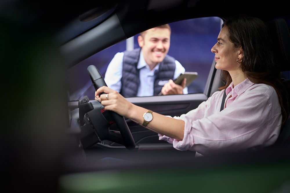 Egy személyt látunk egy Ford vezetőülésében, aki egy táblagépet tartó technikusra néz.