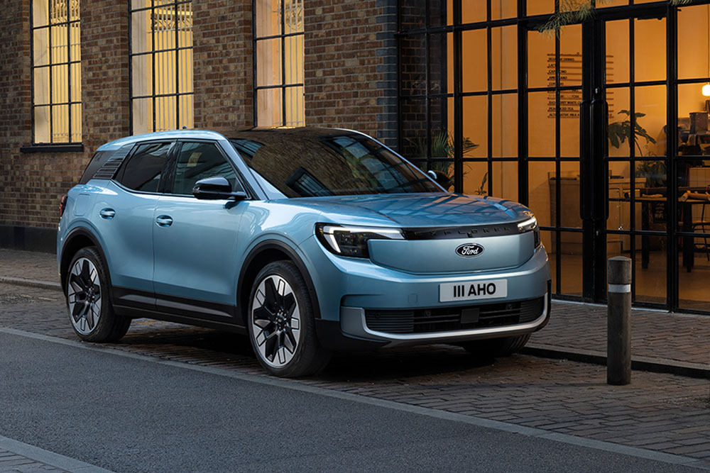 Oldalnézetből látunk egy macskaköves utcán álló téglaépület előtt parkoló világoskék Ford Explorert.