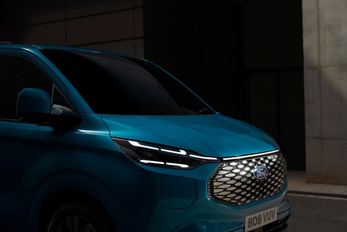 Közelképen látunk egy kék színű, elektromos Ford E-Transit Custom áruszállítót.