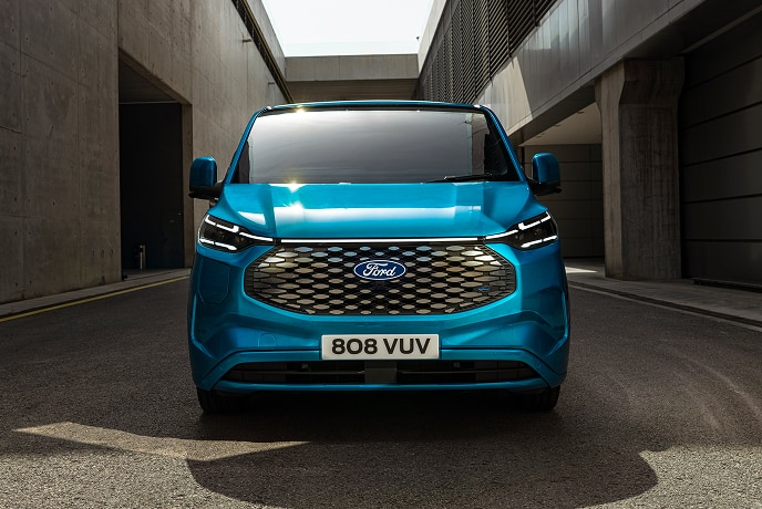 Elölnézetből látunk egy kék színű, elektromos Ford E-Transit Custom áruszállítót.