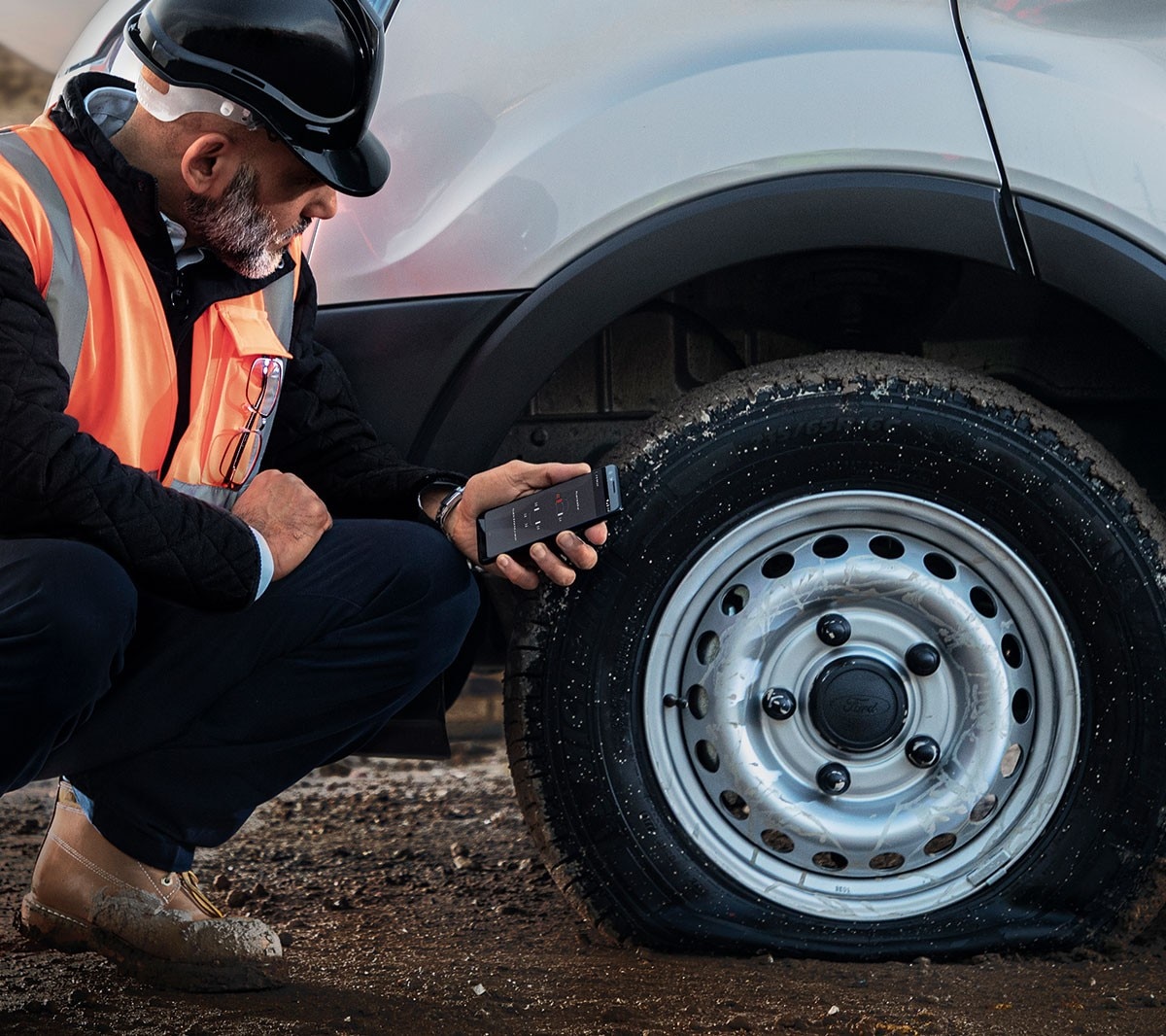 Service person in high viz jacket checking flat tyre