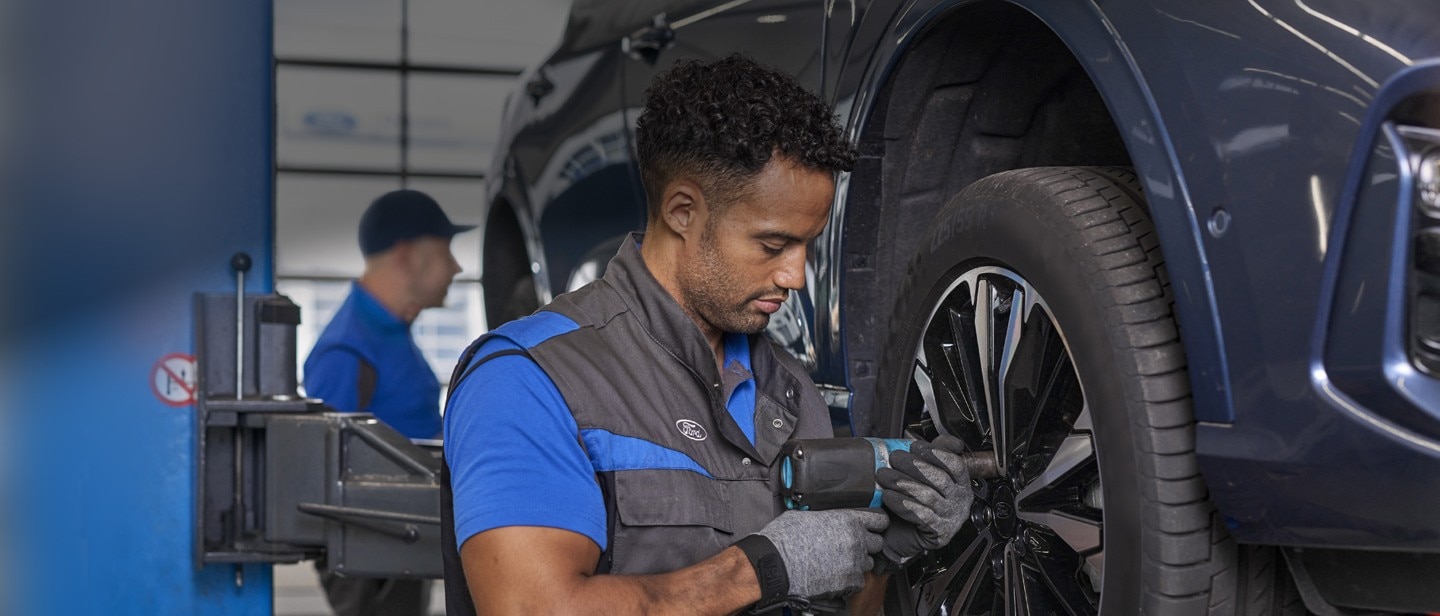 Technician looking under cars hood